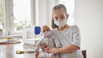 Ein Mädchen und ihre Puppe mit handgenähten Masken.