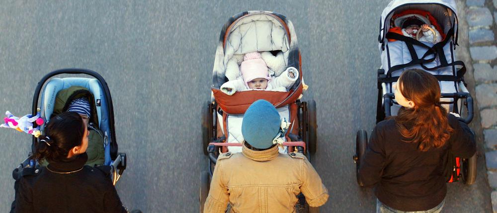 Drei junge Mütter schieben ihre Babys im Kinderwagen bei einem gemeinsamen Spaziergang. (Symbolbild)