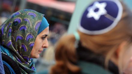 Eine Muslimin mit Kopftuch und eine junge Frau mit Kippa nehmen in Berlin gemeinsam an einer Demonstration teil