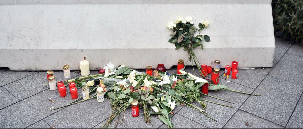 Blumen und Kerzen stehen an einer der Betonbarrieren auf dem Breitscheidplatz. 