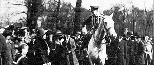 Kronprinz Wilhelm auf einem Pferd im Gespräch mit einem Kindermädchen, umgeben von einer Menschenmenge.
