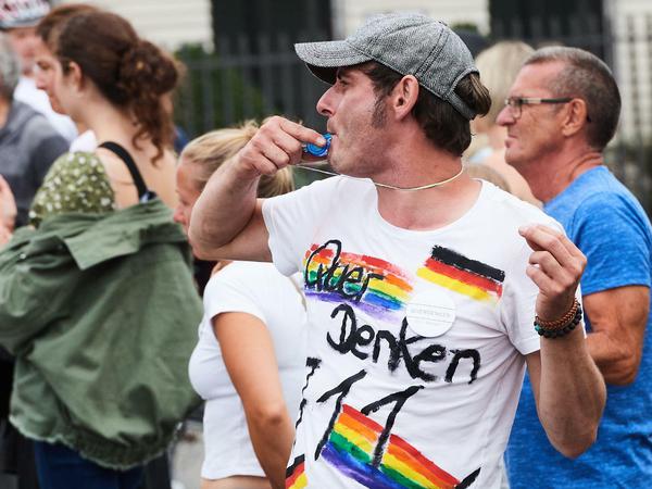  «Querdenken 711» steht auf einem T-Shirt, das ein Demonstranten am Brandenburger Tor bei der Demo Anfang August trägt während er mit einer Trillerpfeife pfeift.