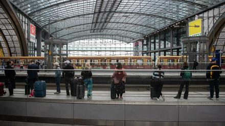 Reisende warten im Hauptbahnhof Berlin auf einen Zug.