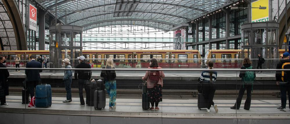Reisende warten im Hauptbahnhof Berlin auf einen Zug.