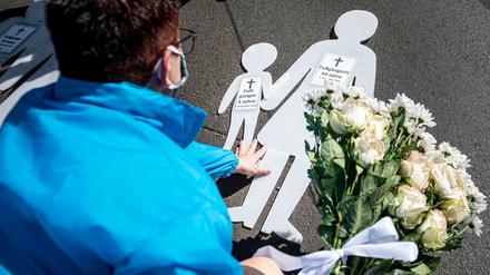 Eine Frau legt bei der Mahnwache zum Jahrestag des SUV-Unfalls in der Invalidenstraße Blumen auf den Boden.