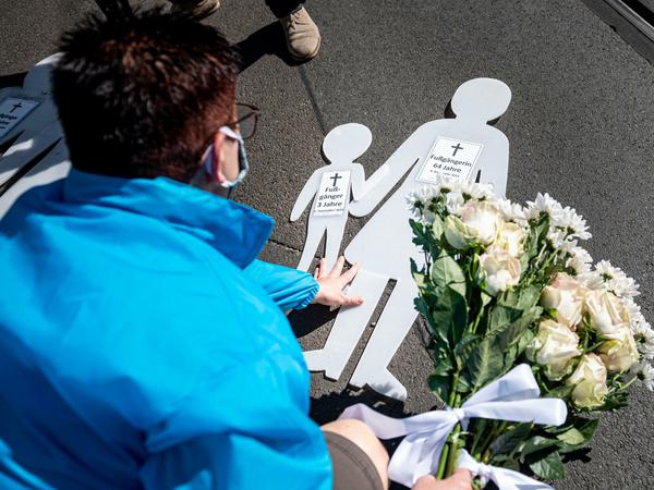Eine Frau legt bei der Mahnwache zum Jahrestag des SUV-Unfalls in der Invalidenstraße Blumen auf den Boden.