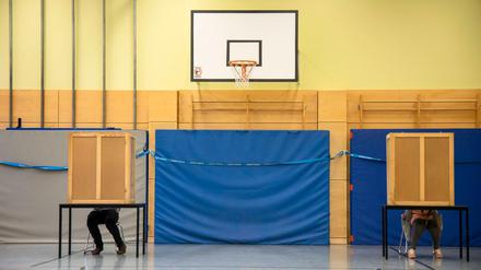 Menschen in einer Wahlkabine in einem Wahllokal in Berlin.