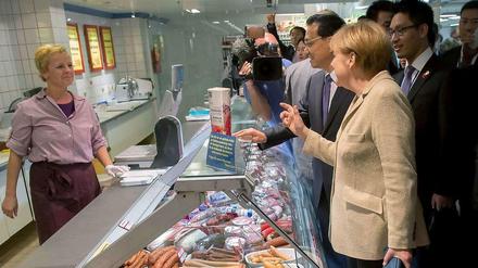 Zwei Wiener, bitte... Kanzlerin Merkel zeigt Chinas Premier Li, wo sie in Berlin einkauft. 