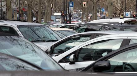 Eng aneinander geparkte Autos unter winterlichen Bäumen in Berlrin.