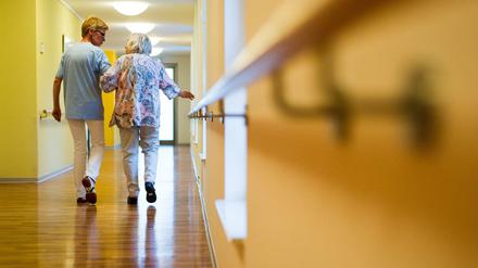 Mit Herz: Eine Pflegekraft begleitet eine ältere Dame im Pflegeheim über einen Korridor.