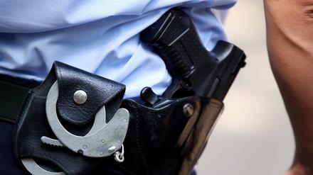 Ein Polizist mit Handschellen und Waffe. (Symbolbild)