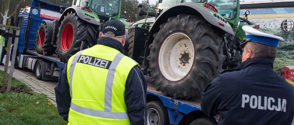 Ein polnischer Polizist und sein deutscher Kollege überprüfen einen polnischen Lkw, beladen mit zwei Traktoren.