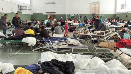 Flüchtlinge in einer Notunterkunft in einer Turnhalle.