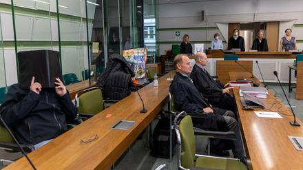 Die Angeklagten sitzen im Gerichtssaal des Kriminalgerichts Moabit hinter ihren Anwälten und verdecken ihre Gesichter.