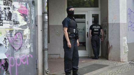 Vermummte Polizisten stehen in Berlin vor einem Haus in Neukölln, andere durchsuchen.