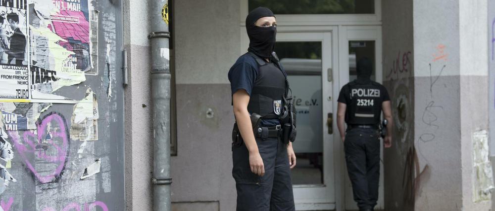 Vermummte Polizisten stehen in Berlin vor einem Haus in Neukölln, andere durchsuchen.