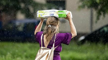 Eine Frau schützt sich am 15. Juli vor dem starken Regenfall mit einer Packung Klopapier.
