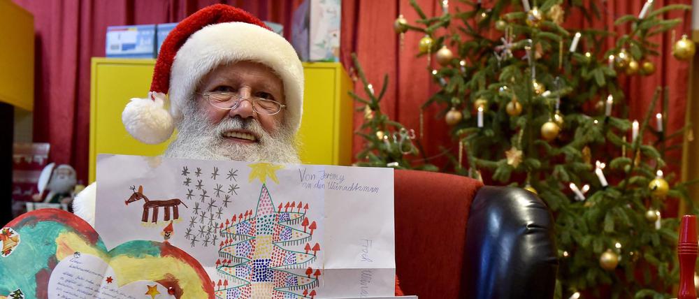 Der Weihnachtsmann zeigt die Wunschzettel von Mia Sophie aus Berlin, Jeremy aus Welzow und Laila aus Berlin.