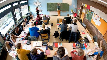 Ein Klassenzimmer mit Schülern, vorn an der Tafel steht die Lehrerin.