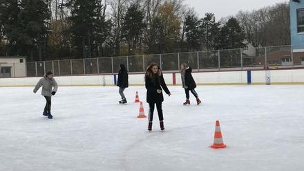 Im Eisstadion üben Schülerinnen und Schüler etwa das Slalomfahren um orangene Hütchen.