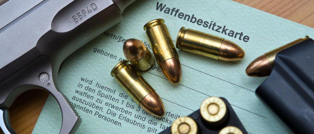 Eine Kaliber 9 mm Pistole, Patronen und ein Magazin liegen auf einer Waffenbesitzkarte. 