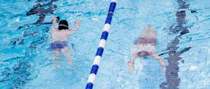 Zwei junge Badegäste schwimmen im Sommerbad Humboldthain. Kinder bis 12 Jahren erhalten in den Sommerferien freien Eintritt - allerdings nur begrenzt.