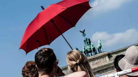 Besucher mit Sonnenschirm vor dem Brandenburger Tor.