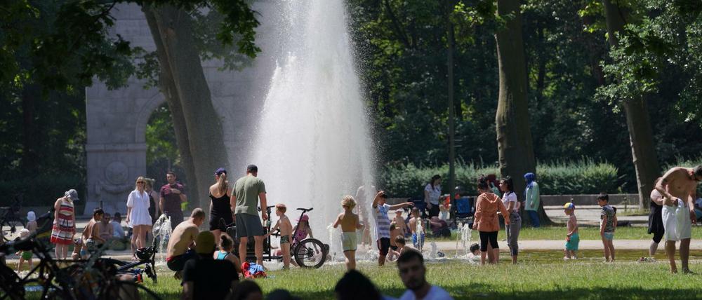 Zahlreiche Menschen suchen bei hochsommerlichen Temperaturen den kühlenden Springbrunnen im Treptower Park auf. 