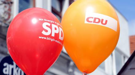 Ein SPD- und ein CDU-Luftballon schweben in der Luft.