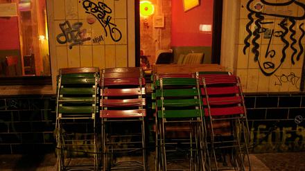 Kurz nach der Sperrstunde stehen zusammengeklappte Stühle vor einer Bar in Neukölln. 