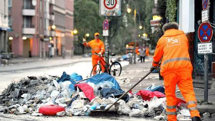 Mitarbeiter der Stadtreinigung fegen den Müll von der Straße.