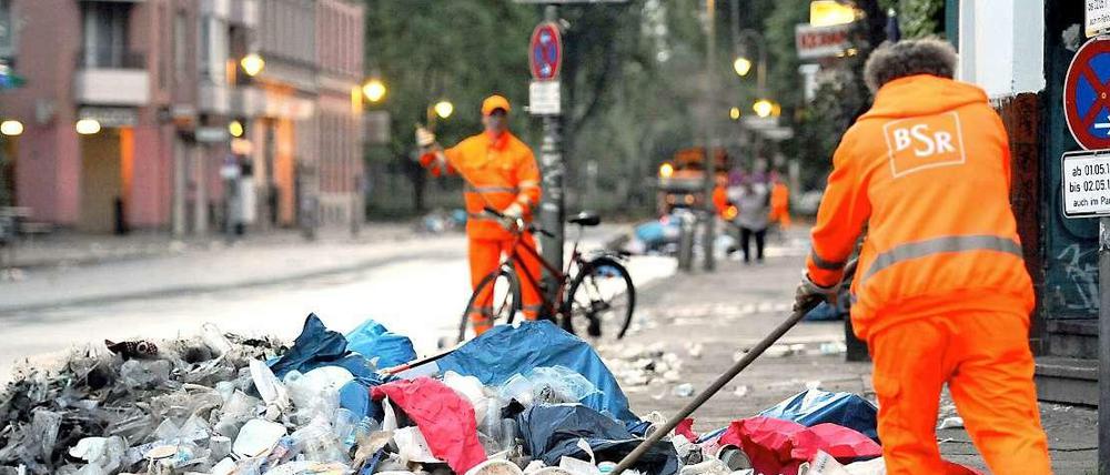 Mitarbeiter der Stadtreinigung fegen den Müll von der Straße.