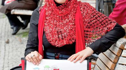 Die türkischstämmige Manar Abdul Ghani sitzt mit ihrer neuen Stadtteilmütter-Tasche in Berlin vor dem Rathaus Neukölln auf einer Bank.