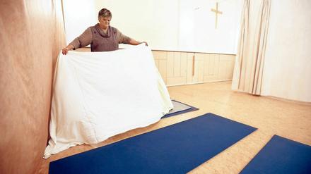 Die Mitarbeiterin einer Notübernachtung in Neukölln bereitet ein Bettenlager für Obdachlose vor. 