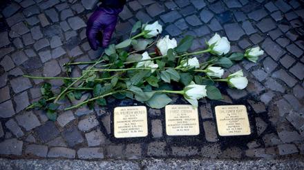 Eine Frau legt am 14.11.2016 in Berlin einen Strauß weißer Roses an den drei Stolpersteinen für verfolgte Berliner Richter während der NS-Zeit vor dem Oberverwaltungsgericht Berlin-Brandenburg nieder. 