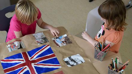 Leonie (li.) und Lilly bereiten im Kinder- und Jugendhaus "Bolle" ein Plakat vor, auf dem die britische Flagge und Fotos von William und Kate zu sehen sind. 