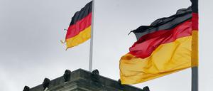 Nicht mehr ganz vollständig: Zerrissene bundesdeutsche Fahnen wehen im Sturm auf und vor dem Reichstagsgebäude.