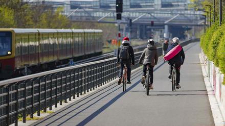  Radfahrende fahren auf einer Fahrradstrasse entlang einer S-Bahnstrecke.