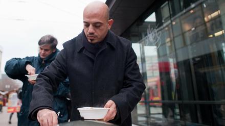 Der aus Damaskus stammende Syrer Alex Assali gibt auf dem Alexanderplatz in Berlin Kartoffeleintopf an bedürftige Menschen aus.