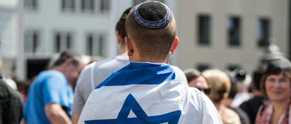 In eine israelische Fahne eingewickelt demonstriert ein Mann im Juli in Bonn gegen Antisemitismus.