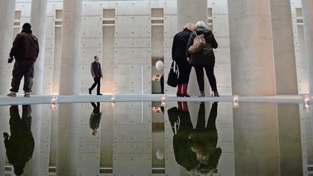 Besucher des Krematoriums Baumschulenweg spiegeln sich in der Kondolenzhalle in einem Wasserbecken. 