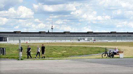 Menschen auf dem Tempelhofer Feld mit Flughafengebäude im Hintergrund, dahinter der Fernsehturm.
