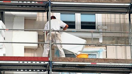 Arbeite dämmen eine Fassade eines Hauses. Künftig werden energetische Sanierungen in Berlin kräftig bezuschusst.