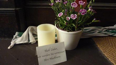 Vor der Wohnungstür des Toten haben Nachbarn eine Blume und eine Kerze aufgestellt.