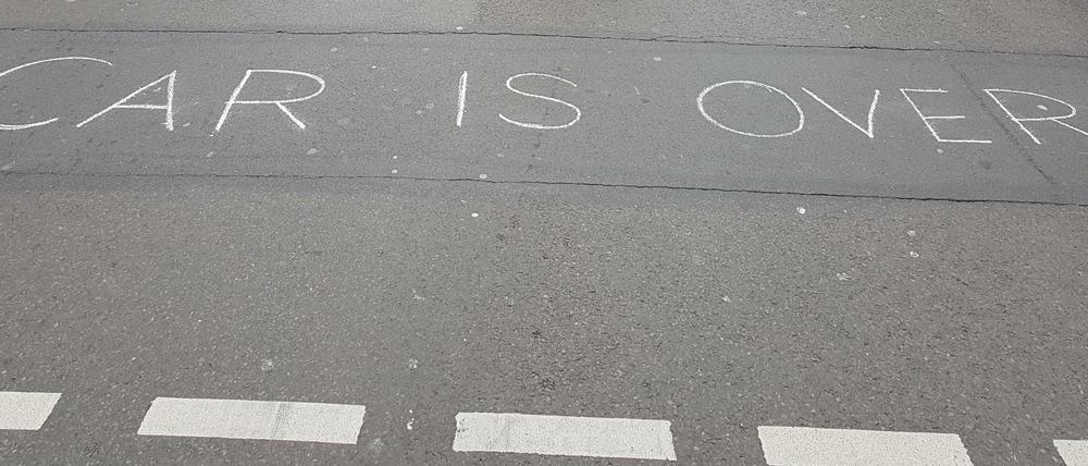 Schriftzug "Car is over" auf Straßenasphalt.