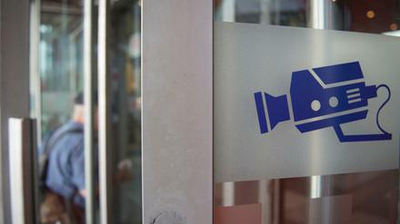 Auf einem Hinweisschild ist eine Kamera abgebildet, aufgenommen an einer Eingangstür zum Bahnhof Südkreuz.