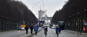 Passanten und Radfahrer sind am 29.12.2017 in Berlin auf der für den Verkehr gesperrten Straße des 17. Juni unterwegs, während im Hintergrund das Riesenrad für Deutschlands größte Silvesterparty aufgebaut wird.
