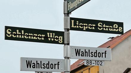 Die alten Straßennamen in Wahlsdorf (Brandenburg) sind durchgestrichen. Nach der Gemeindereform wurden neue Schilder angebracht, die den Weg zu den durchnummerierten Häusern weisen.