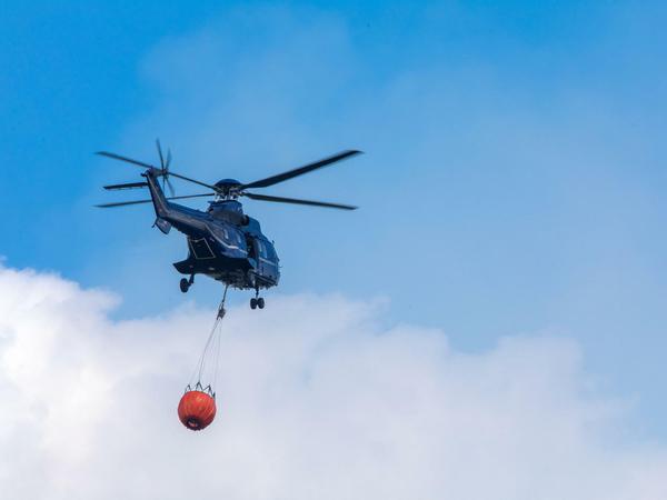 Ein Hubschrauber der Bundespolizei transportiert Löschwasser zu einem Brandherd in der Nähe der evakuierten Ortschaft Alt Jabel.