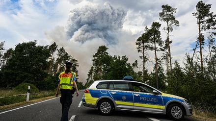 Ein Polizei Auto sperrt die Straße in einem Waldbrandgebiet in der Gohrischheide ab. In der Gohrischheide an der Landesgrenze zu Brandenburg ist ein munitionsbelastetes Waldstück in Brand geraten.